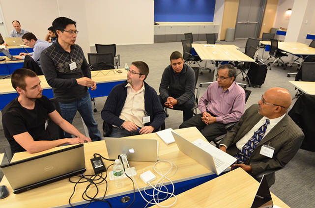 A team from IBM, DAH, and Altoros works on combining code. Group leader Robert Fajta is in yellow shirt in center.